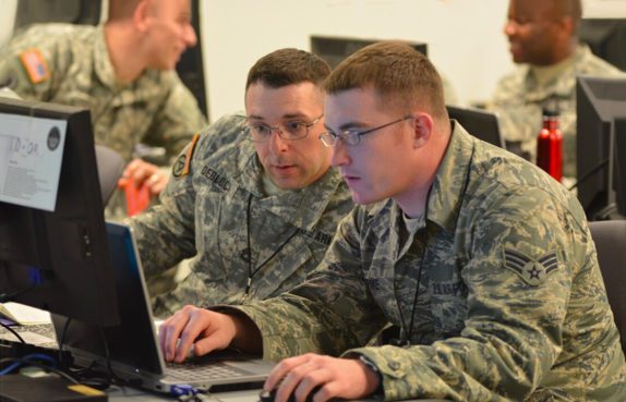 Two soldiers at a laptop discussing cyber shield exercise