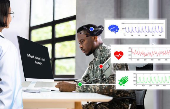 Solider at computer being evaluation with text and images on a screen. Overlay of physiological response graphs.